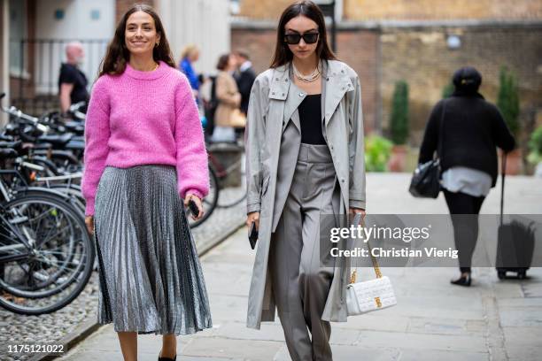 Erika Boldrin wearing pink knit, silver pleated skirt and Beatrice Gutu wearing grey trench coat, pants is seen outside Erdem during London Fashion...