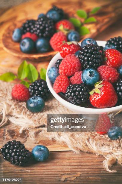 fresh berries in a bowl on rustic wooden background. - berry fruit stock pictures, royalty-free photos & images