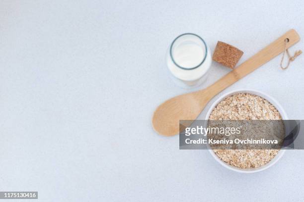 oat flaks on a wooden spoon and jug of milk. - kli bildbanksfoton och bilder