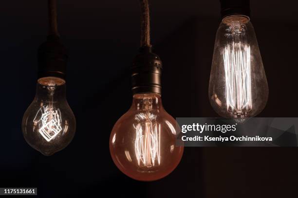 a classic edison light bulb on black background - edison bulb stockfoto's en -beelden