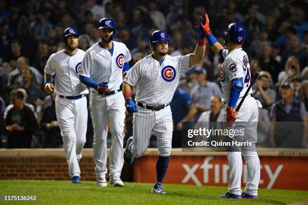 Willson Contreras of the Chicago Cubs congratulates Kyle Schwarber of the Chicago Cubs for his three run home run in the first inning against the...