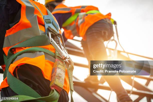 [safety body construction] working at height equipment. fall arrestor device for worker with hooks for safety body harness on selective focus. worker as in construction background. - sicherheitsgurt sicherheitsausrüstung stock-fotos und bilder