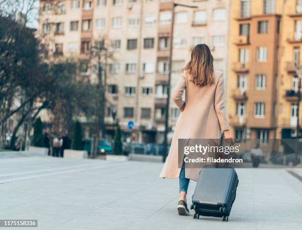 woman walking with suitcase - wheeled luggage stock pictures, royalty-free photos & images