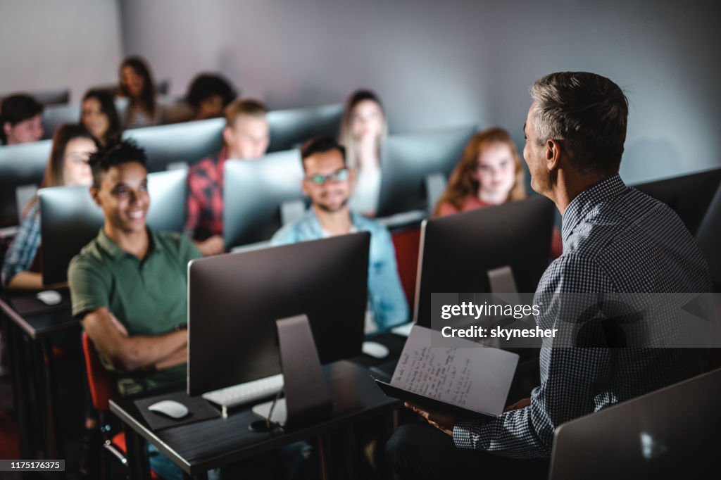 Mid adult male teacher teaching the lecture in computer lab.