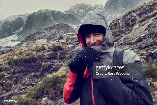 male hiker with hood up in sleeting snow capped mountain landscape, portrait, llanberis, gwynedd, wales - schneeregen stock-fotos und bilder