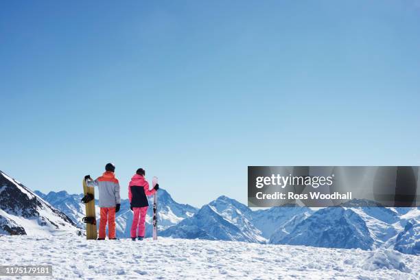 teenage boy snowboarder with sister skier looking out from snow covered mountain top, rear view,  alpe-d'huez, rhone-alpes, france - neige épaisse photos et images de collection