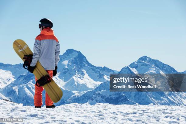 teenage boy snowboarder looking out over landscape from snow covered mountain top, rear view, alpe-d'huez, rhone-alpes, france - スノーボード ストックフォトと画像