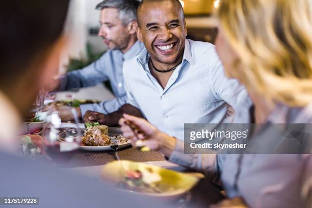 happy black businessman talking to his colleague during lunch in a restaurant. - smart casual lunch stock pictures, royalty-free photos & images