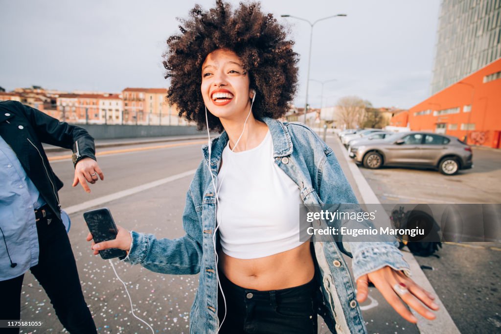 Friends dancing in street to smartphone music, Milan, Italy