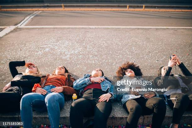 friends lying on kerb, milan, italy - kerb stock pictures, royalty-free photos & images