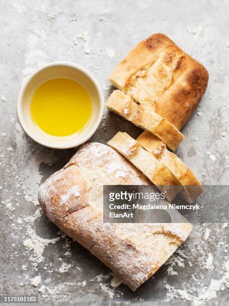 still life of floured and unfloured ciabatta loaf on baking tray with bowl of olive oil, overhead view - white bread fotografías e imágenes de stock