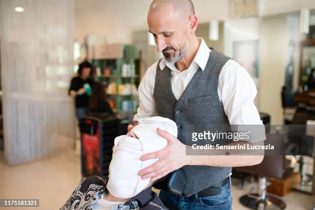 hairdresser drying customer's face and hair with towel in barber shop - barber shop 3 stock pictures, royalty-free photos & images