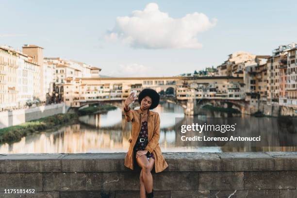 young woman with afro hair taking selfie on bridge, florence, toscana, italy - florenz italien stock-fotos und bilder