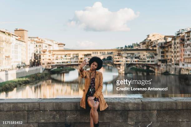 young woman with afro hair taking selfie on bridge, florence, toscana, italy - florence italy stock pictures, royalty-free photos & images