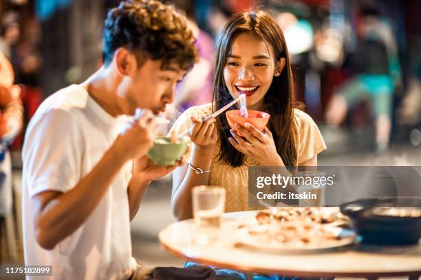 asiatisches paar genießt street food in hongkong - chinesische küche stock-fotos und bilder