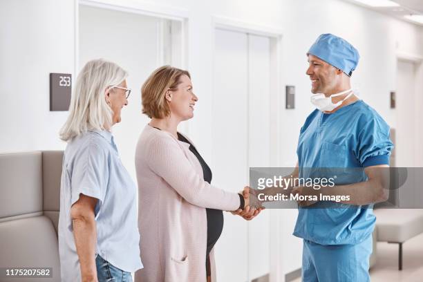 mannelijke arts schudden handen met zwangere patiënt - pregnant women greeting stockfoto's en -beelden