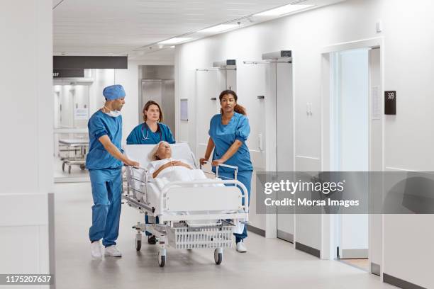 artsen duwen senior patiënt op hospital gurney - hospital gurney stockfoto's en -beelden