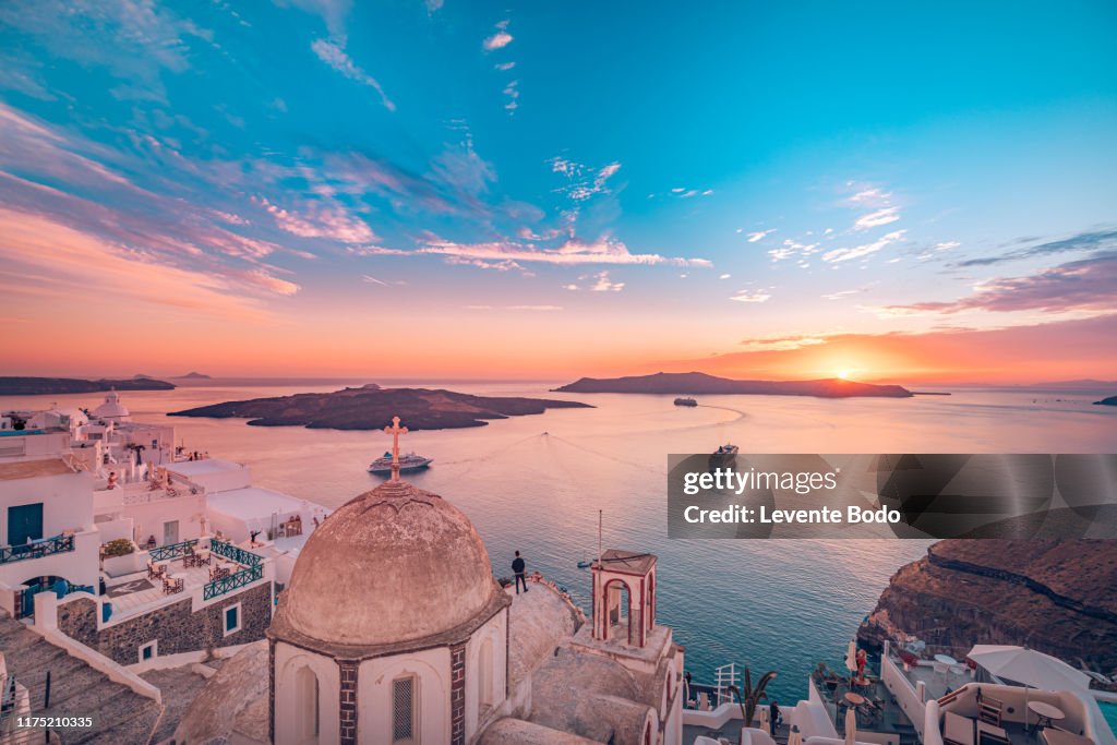 Amazing evening view of Fira, caldera, volcano of Santorini, Greece with cruise ships at sunset. Cloudy dramatic sky