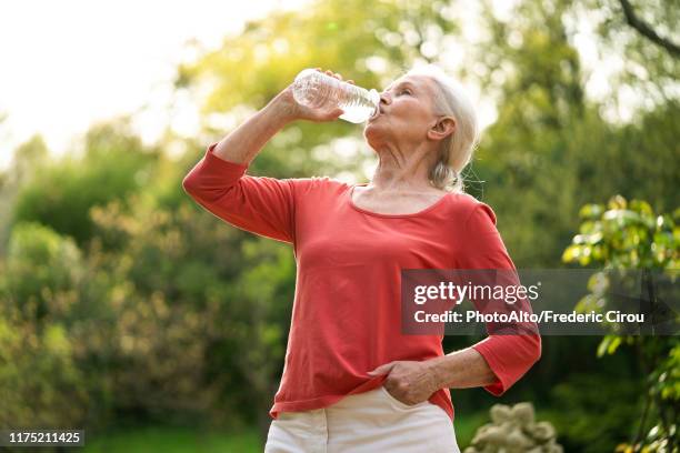 senior woman drinking water - woman drinking water from bottle stock-fotos und bilder