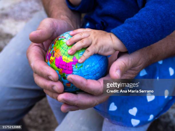 the hands of a grandfather and a baby with a globe in their hands. ecology and globalization concept - westernization stock pictures, royalty-free photos & images