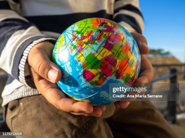 the hands of a child with a globe in his hands. ecology and globalization concept - kartographie stock-fotos und bilder