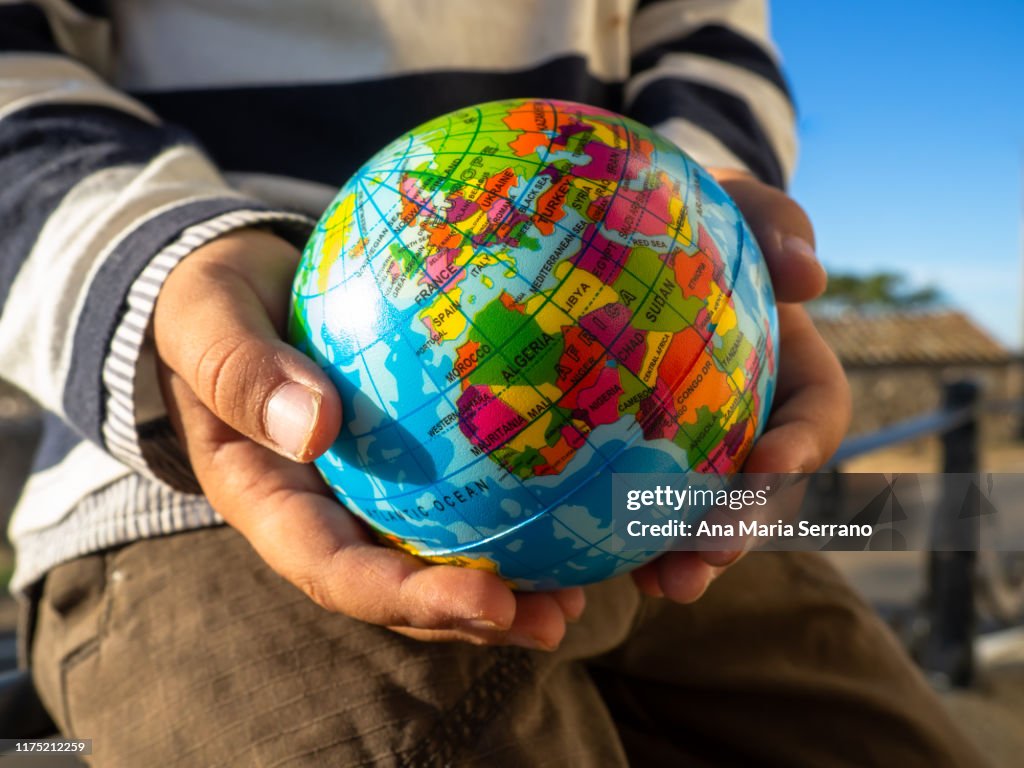 The hands of a child with a globe in his hands. Ecology and globalization concept