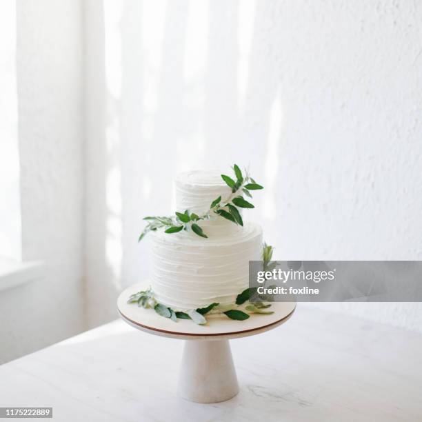 two tiered wedding cake with icing and olive branch decoration - wedding cakes stock pictures, royalty-free photos & images