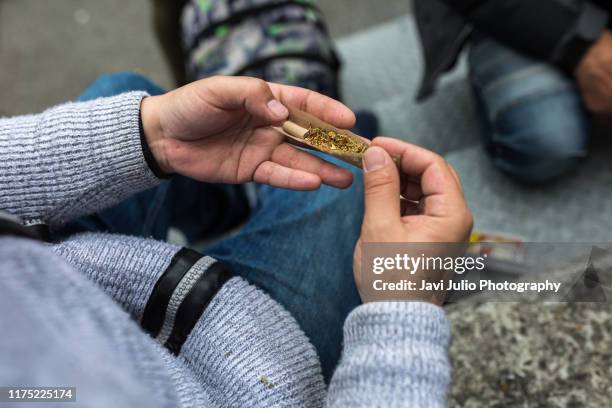 a person messes up a joint of marijuana - marihuana hierba de cannabis fotografías e imágenes de stock