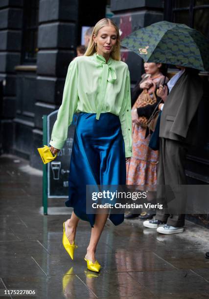 Leonie Hanne is seen wearing navy silk skirt, green blouse with tie, yellwo mini bag Jacquemus outside Christopher Kane during London Fashion Week...