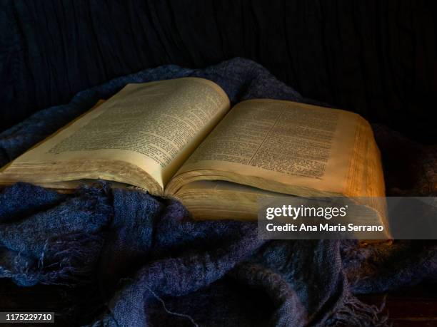 a still life with an open ancient bible on a dark old cloth that symbolizes the passage of time - sect stockfoto's en -beelden