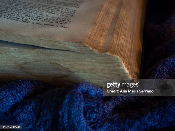 a still life with an open ancient bible on a dark old cloth that symbolizes the passage of time - quran stock pictures, royalty-free photos & images