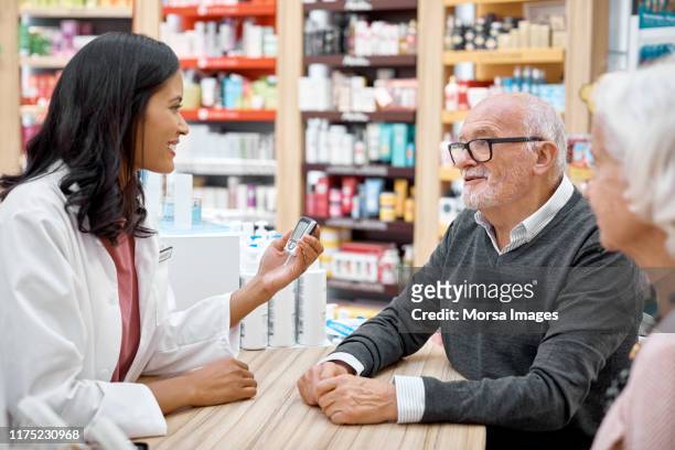senior couple looking at young doctor at pharmacy - pharmacist and patient stock pictures, royalty-free photos & images