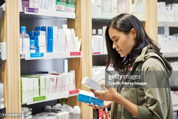 customer comparing medicines by rack at pharmacy - use by label bildbanksfoton och bilder