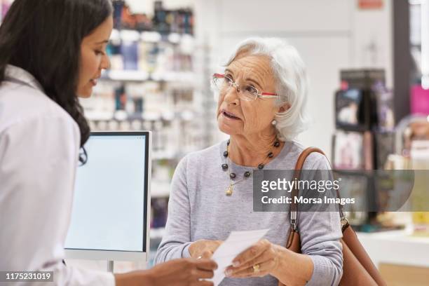 elderly customer showing prescription to doctor - apotheke rezept stock-fotos und bilder
