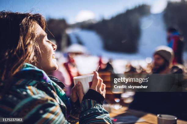 gelukkige vrouw genieten in zon en thee bij ski resort. - happy skier stockfoto's en -beelden