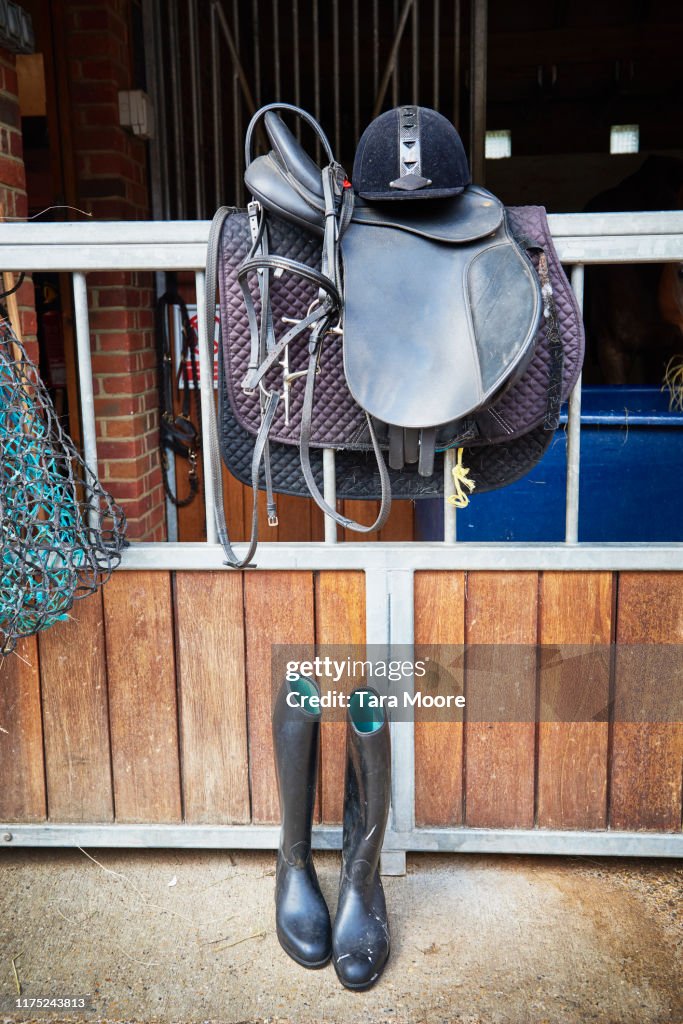 Bridle, saddled and ridding boots in stables