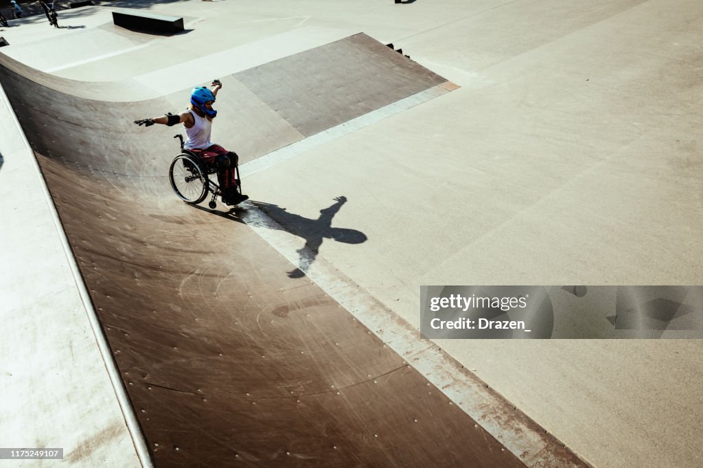 Disabled woman in wheelchair doing stunts in skate park