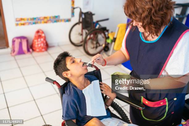working in nursery with children with learning difficulties - boy in wheelchair with celebral palsy - learning disability nurse stock pictures, royalty-free photos & images