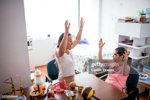 hispanic teacher playing with woman with down syndrome - learning disability nurse stock pictures, royalty-free photos & images