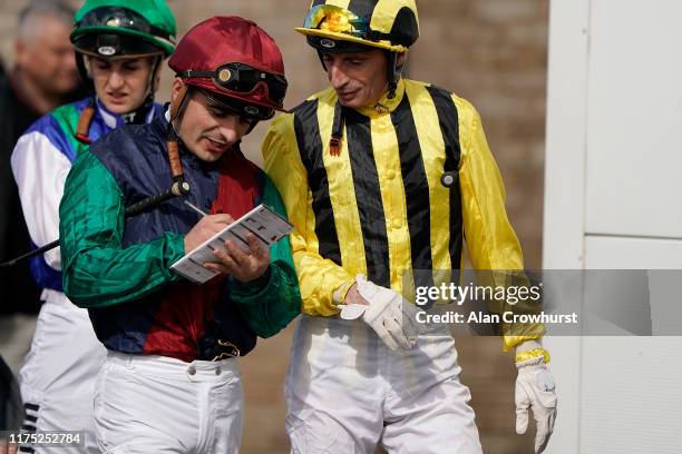 Jockey Andrea Atzeni signs an autograph as Gerald Mosse looks on at Yarmouth Racecourse on September 17, 2019 in Yarmouth, England.