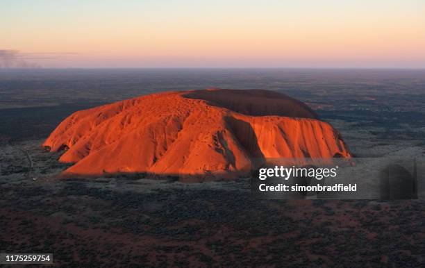 aerial view of uluru in the evening sun - uluru stock pictures, royalty-free photos & images