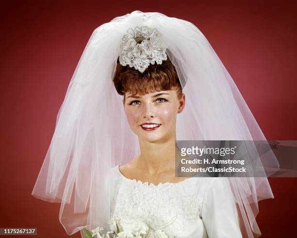 1960s SMILING HAPPY BRIDE PORTRAIT WEARING WHITE WEDDING GOWN BRIDAL BOUQUET FLOWERS SHORT NET VEIL LOOKING AT CAMERA