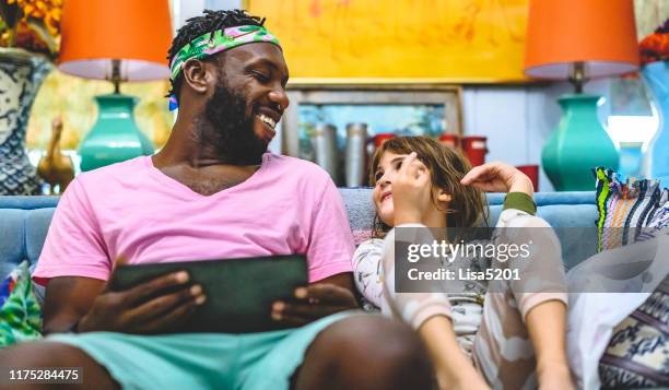 african american man and stepdaughter little girl child use a digital tablet at home together - colourful home stock pictures, royalty-free photos & images