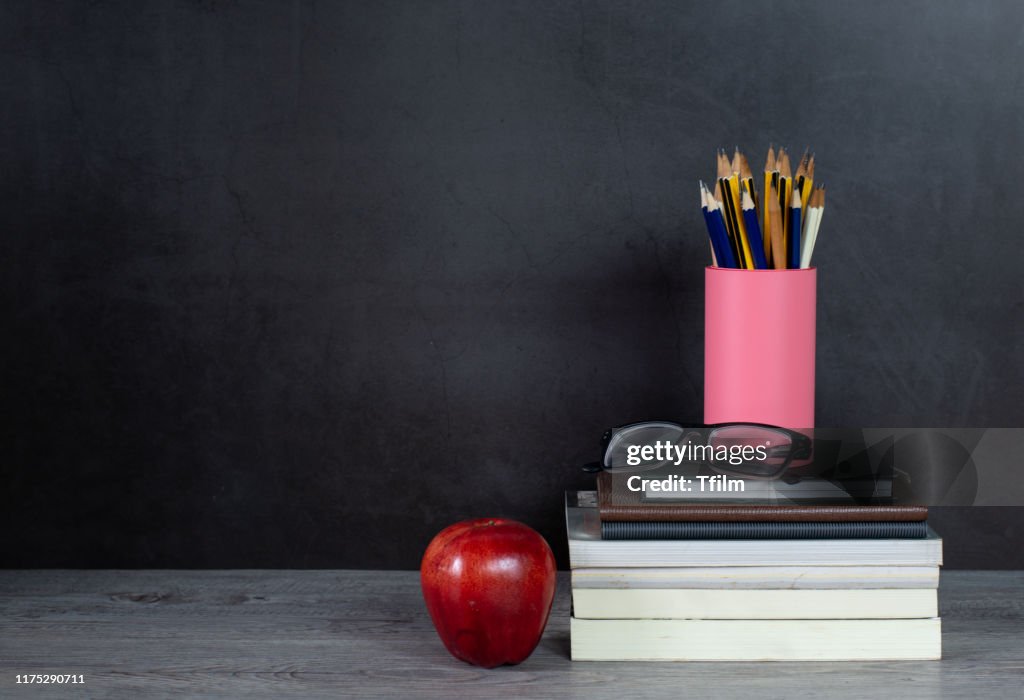 Stack of books and pencil on the table with blackboard background