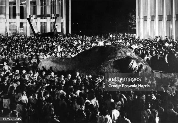 Scene from the film 'King Kong' depicts a crowd gathered around the titular character at the foot of the World Trade Center, New York, New York, 1976.