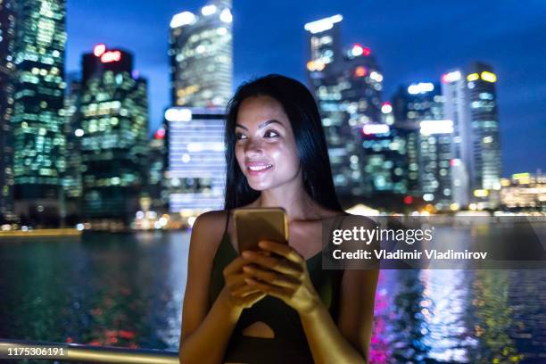 beautiful woman using smart phone at night - singapore night stock pictures, royalty-free photos & images