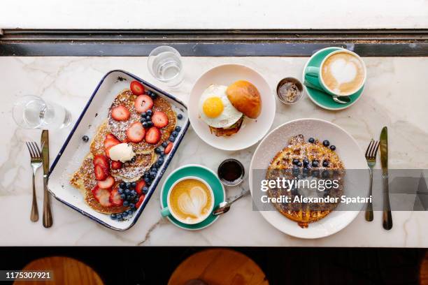 directly above view of a brunch with pancakes, waffle and burger with fried egg in a restaurant - brunch stock-fotos und bilder