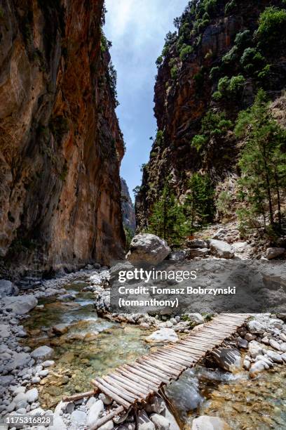 a stream and a small wooden bridge in the rocky scenery of samaria gorge, the largest canyon in europe. white mountains (lefka ori), crete, greece. - kreta stockfoto's en -beelden