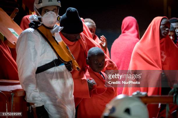 Man standing with his young boy among other rescued migrants waits onboard the Spanish Maritime vessel, to disembark, in Malaga, southern of Spain,...