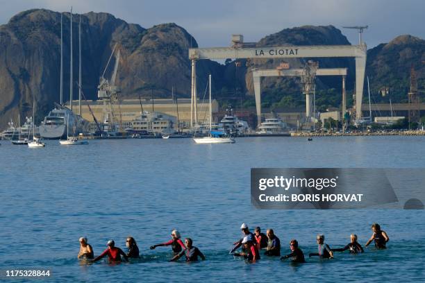 People practice "Longe-Cote" or "Sea Wading" in La Ciotat on October 11, 2019 with, background, the shipyard.